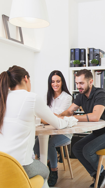 Smiling man and woman sitting and talking with their daughter at a table in a law office.